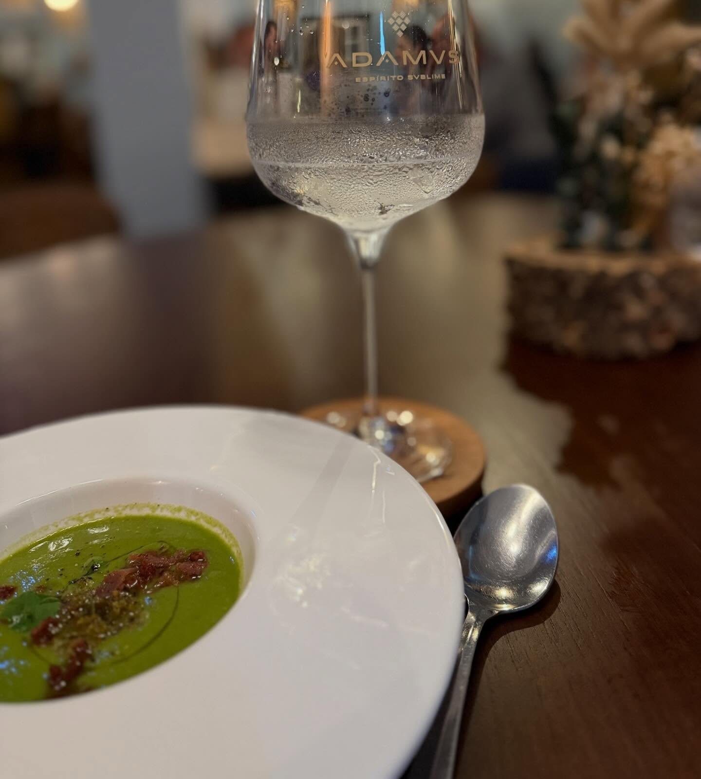 Prato de creme de ervilhas com presunto, ao lado de um copo de vinho branco