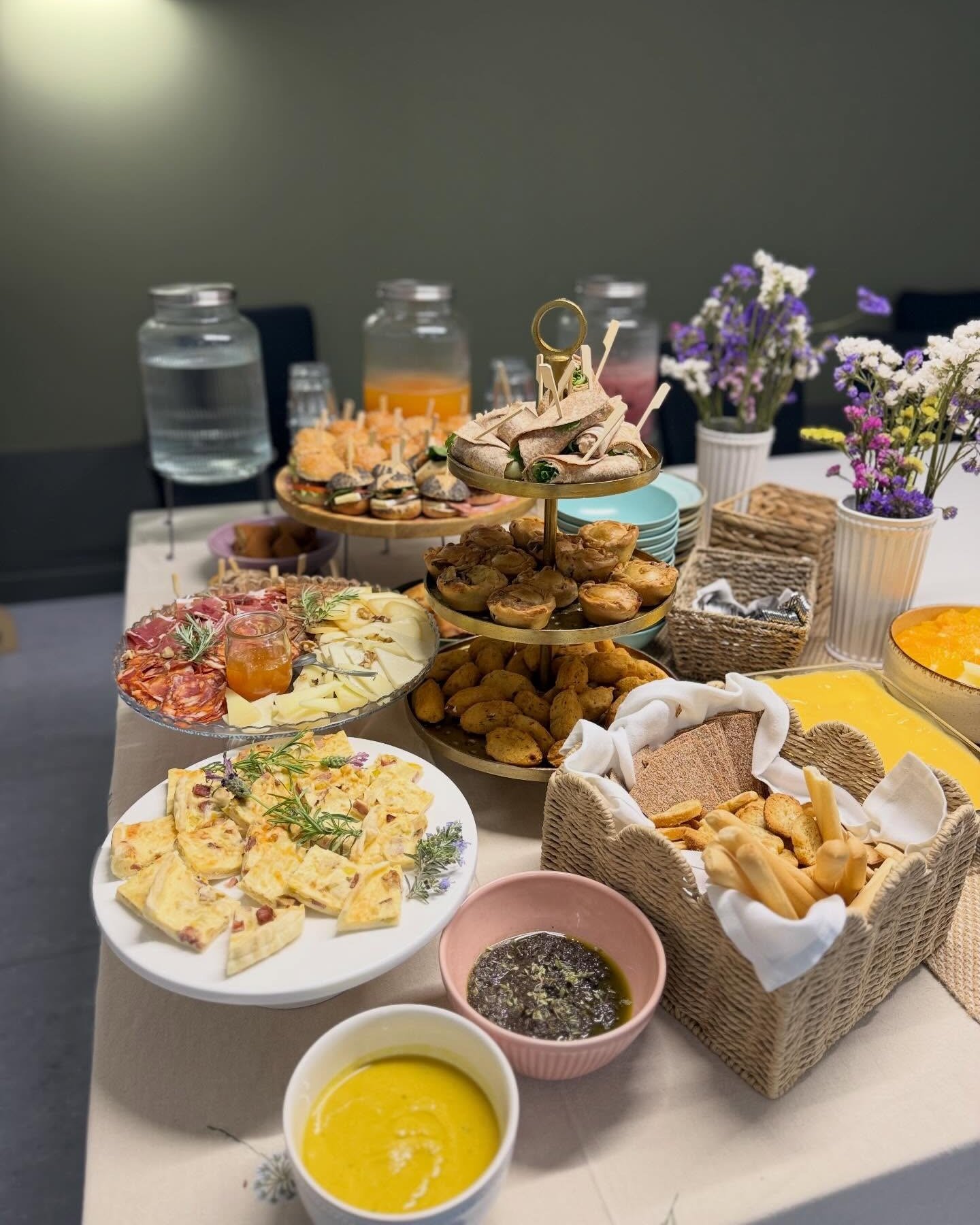 Petiscos para partilhar: enchidos e queijos, quiche, folhados, pão e creme, com flores do campo